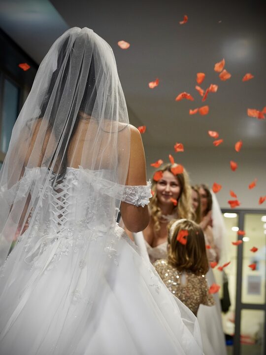 Rosenblätter fliegen über zwei Bräute in der Boutique