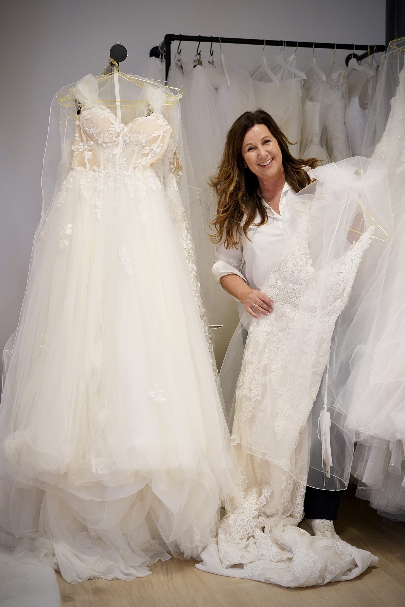 Ulrike Pausch zwischen den Kleiderstangen der Herzspinnerei, ein Spitzenkleid über dem Arm, daneben ein Tüllkleid auf dem Bügel