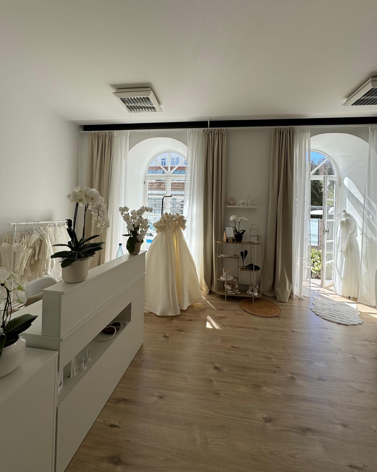 Der Ankleideraum der Herzspinnerei: zwei Rundbogenfenster der Alten Spinnerei, Vorhänge, Orchideen und Brautkleider an der Wand